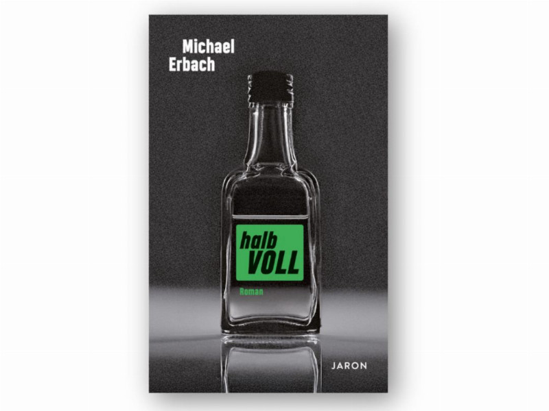 Eine leere, durchsichtige Miniaturflasche mit grünem Etikett steht vor dunkelgrauem Hintergrund und spiegelt sich auf glänzender Fläche.