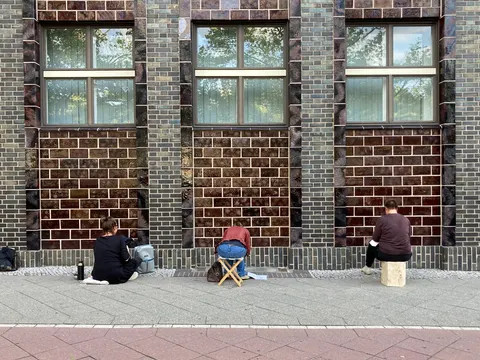 Drei Menschen sitzen vor der Wand mit rücken zur Kamera
