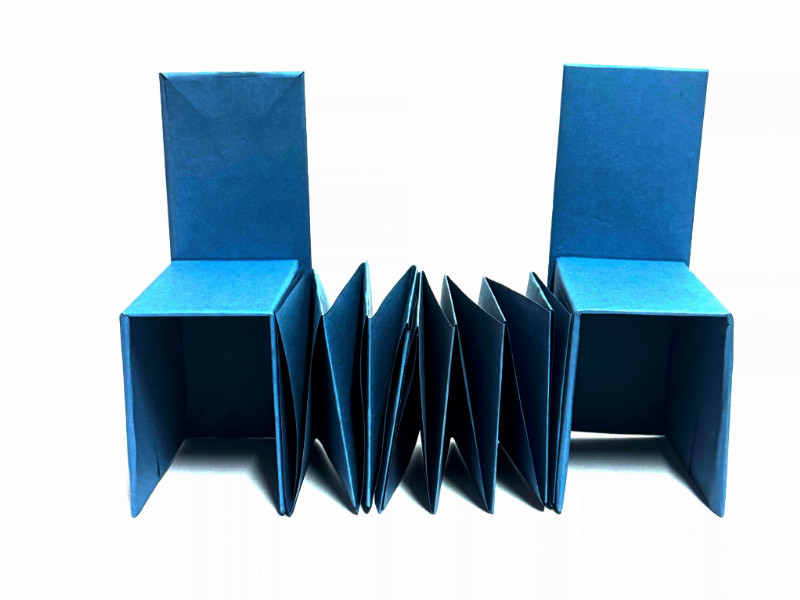 Da sind 2 Stühle die miteinander verbunden sind und aus Papier gebastelt wurden sind 
