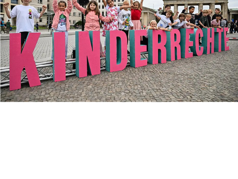 Foto mit Kindern, die hinter einem großen Schriftzug KINDERRECHTE stehen