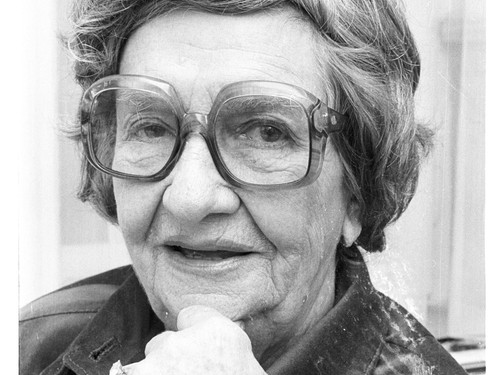 Eine Dame schaut in die kamera. Das BIld ist schwarz weiß und sie hat eine große Brille auf