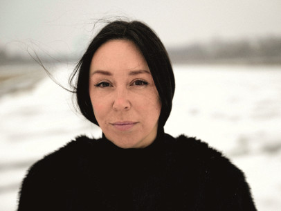 Eine schwarzhaarige Frau schaut in die Kamera. Sie ist draußen und es liegt Schnee.