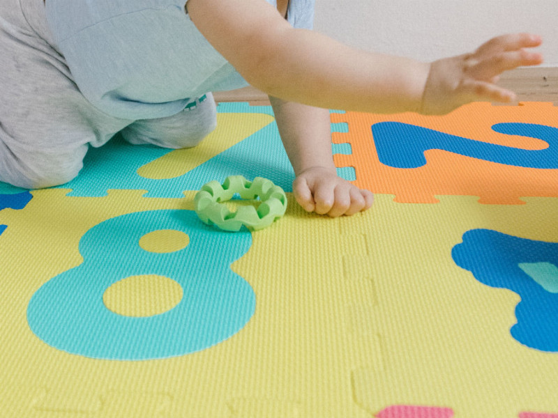 Ein Kind krabbelt auf einer bunten Matte