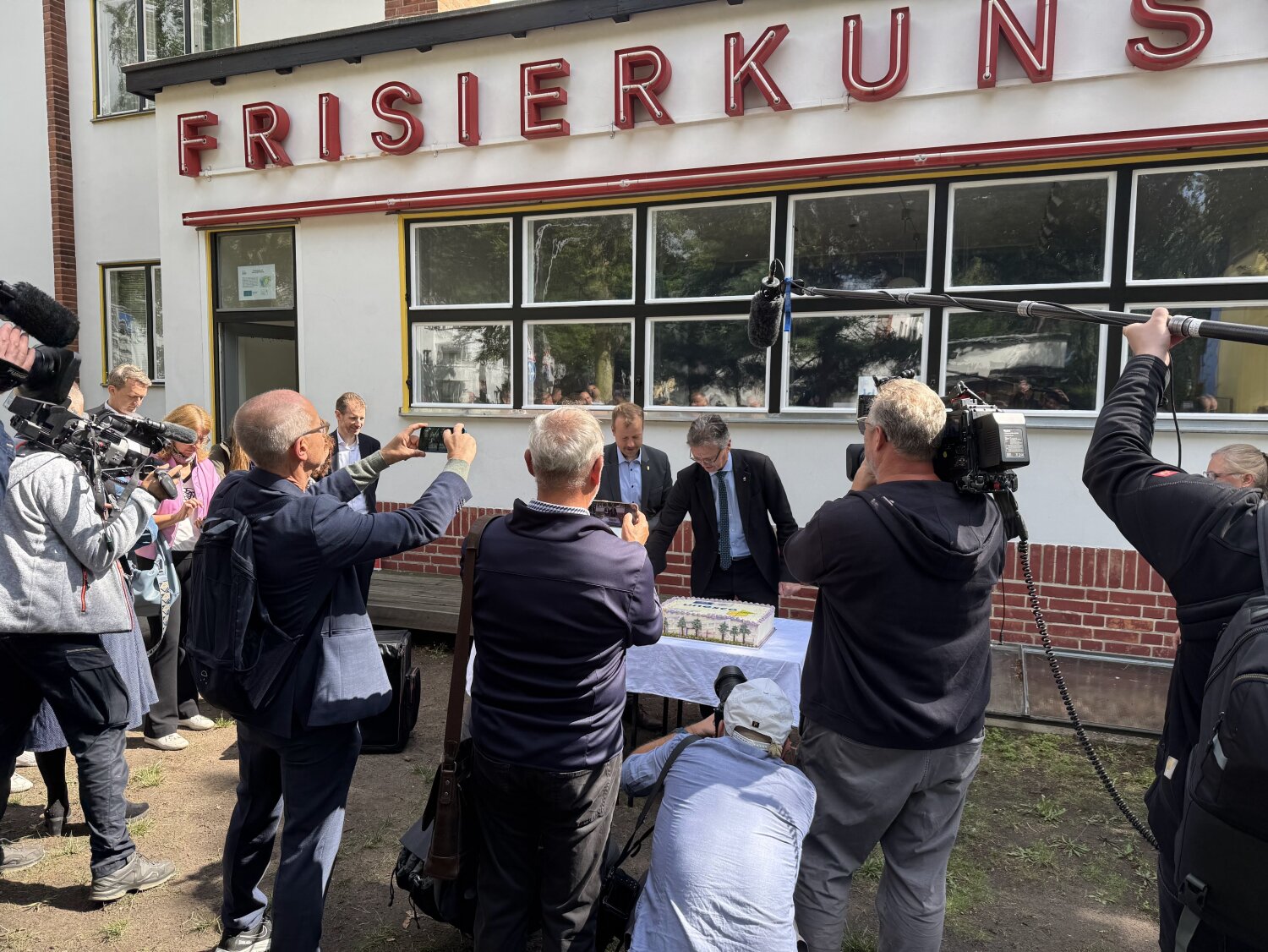 Vor dem Kieztreff in der Waldsiedlung Zehlendorf wird der Welterbekuchen angeschnitten und gemeinsam angestoßen