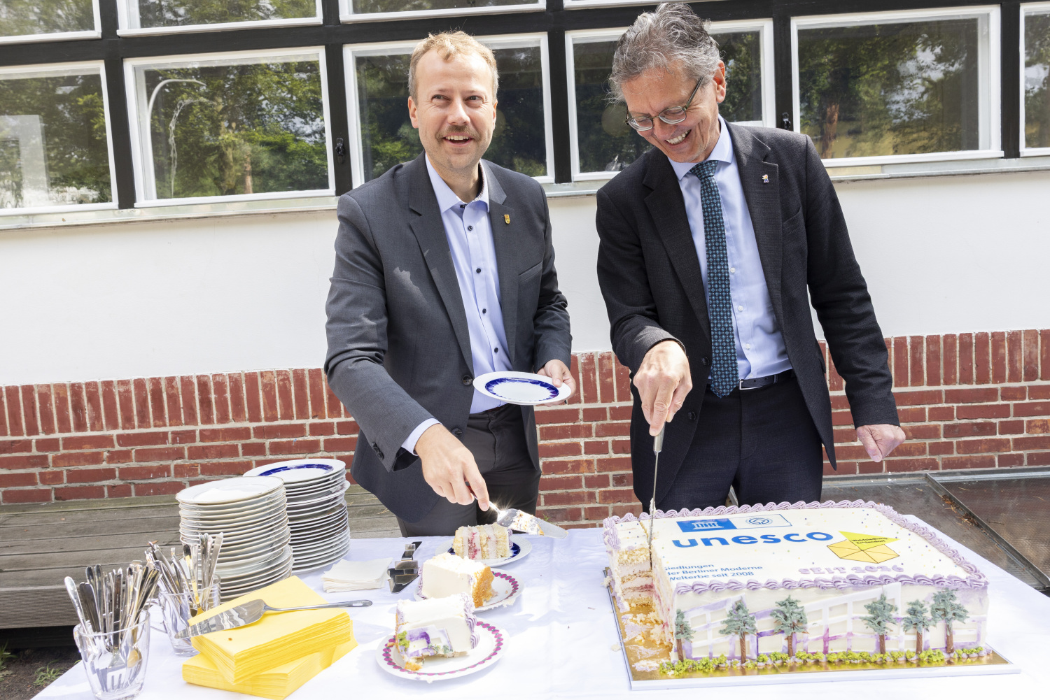 Senator Christian Gaebler und Bezirksstadtrat Patrick Steinhoff verteilen den Welterbekuchen an die Gäste