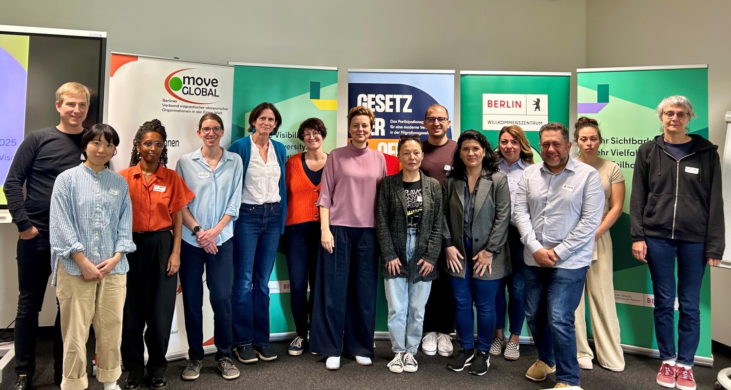 Eine Gruppe Menschen steht vor Bannern.