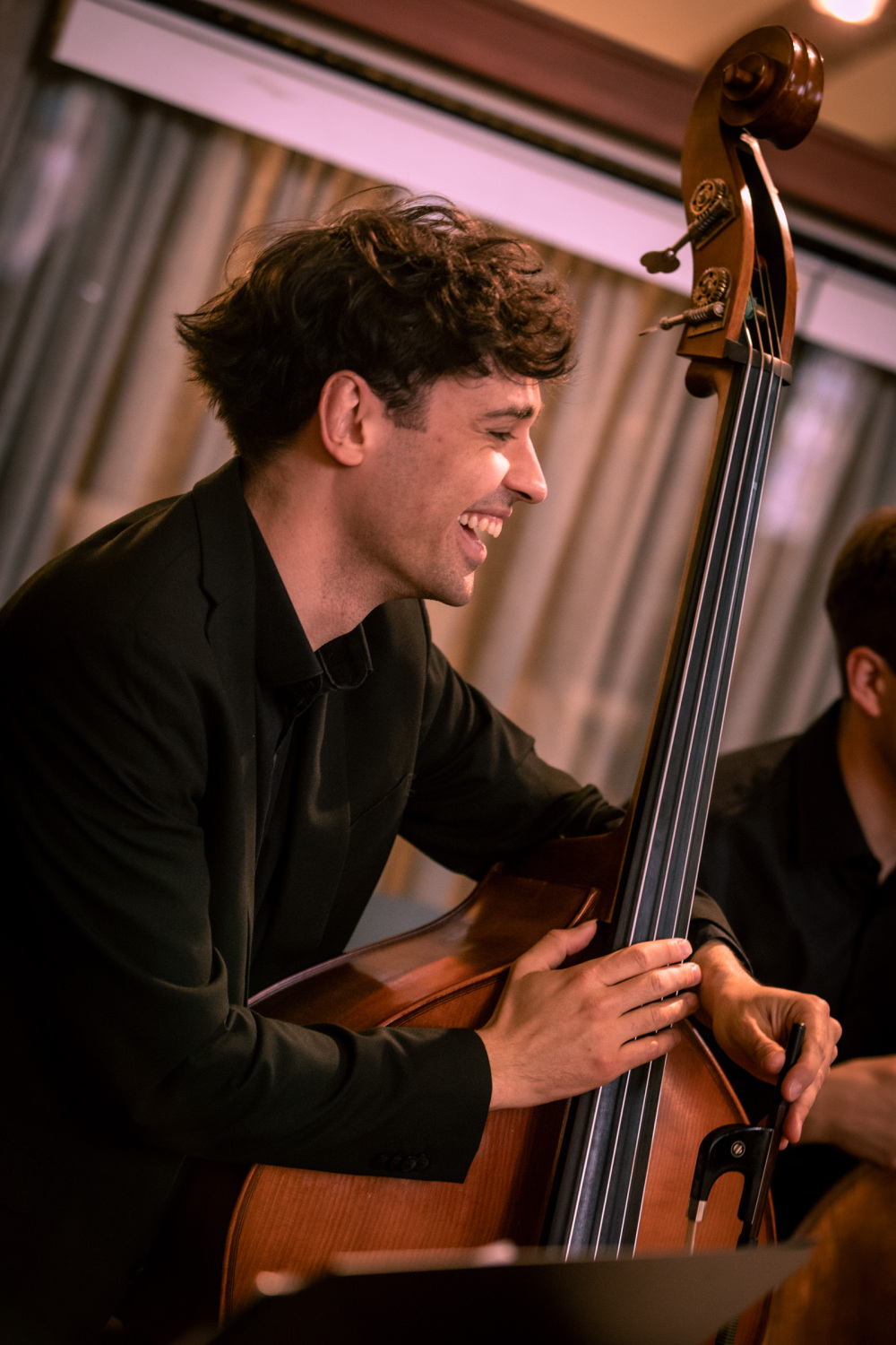 Junger Mann lacht beim Kontrabass-Spielen