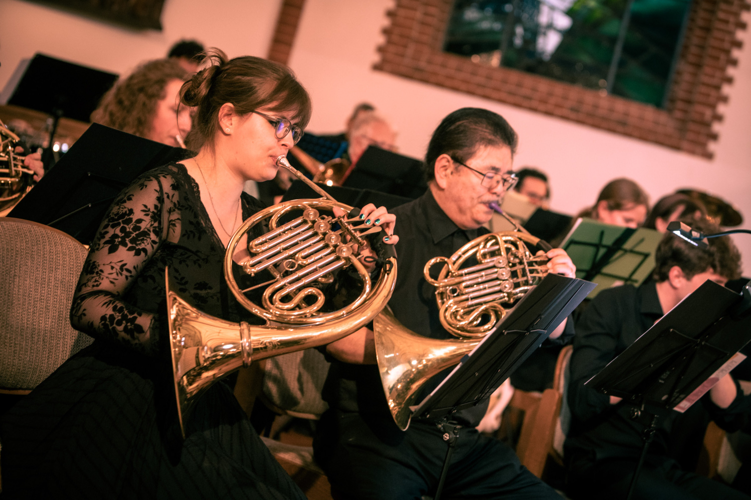 Mehrere Menschen spielen Horn im Orchester