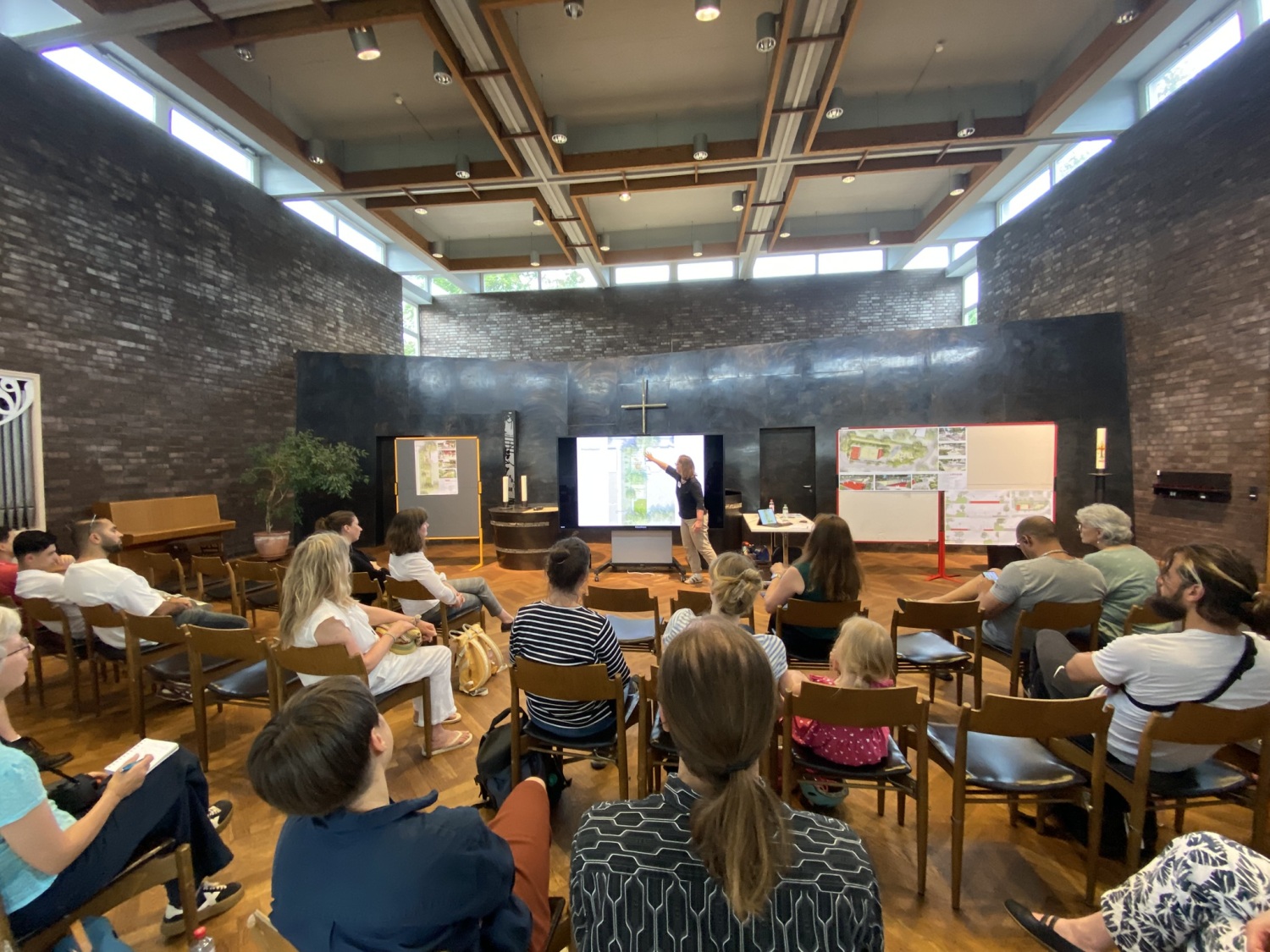 Menschen sitzend vor Stellwänden mit Plänen