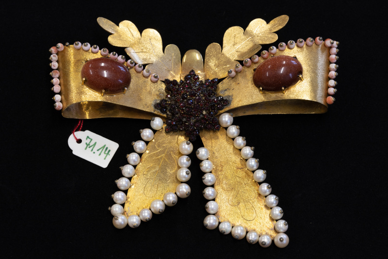 Anstecker, 585/f, Gelbgold, in Schleifenform mit mehreren Perlen, roten und braunen Steinen