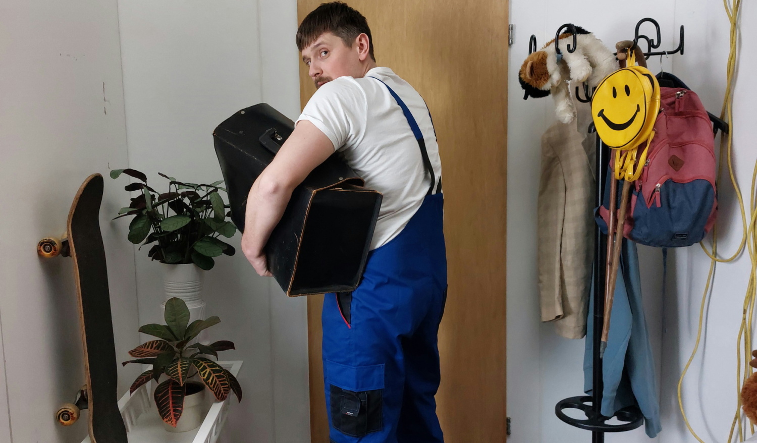 Ein Mann, der wie ein Handwerker angezogen ist, verlässt schleichend eine Wohnung