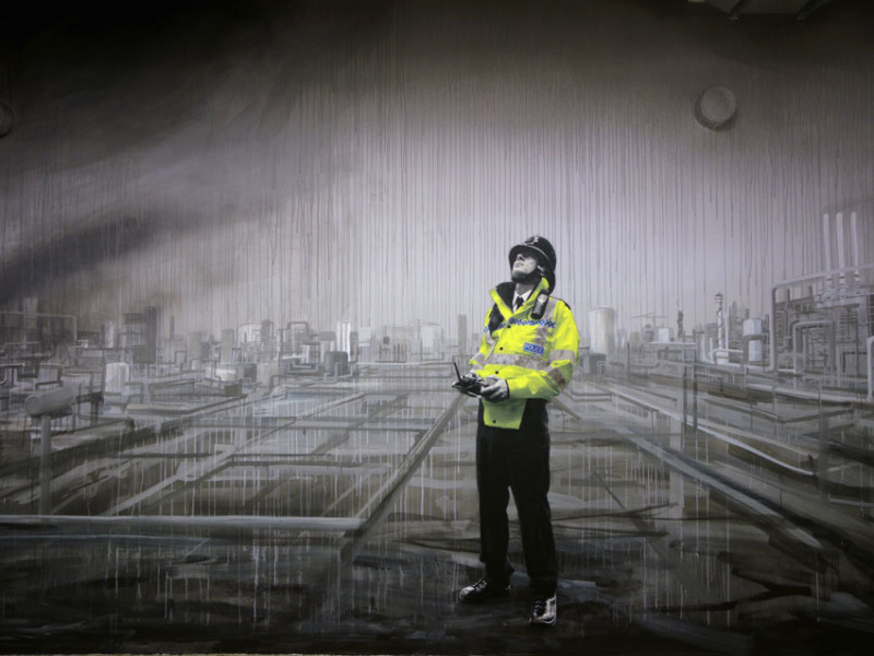 Britischer Polizist steht im Regen und schaut zum Himmel