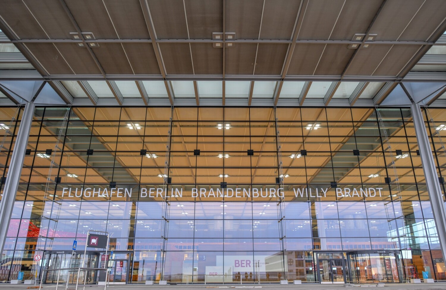 Gläserner Eingangsbereich des BER mit dem Schriftzug Flughafen Berlin Brandenburg Willy Brandt
