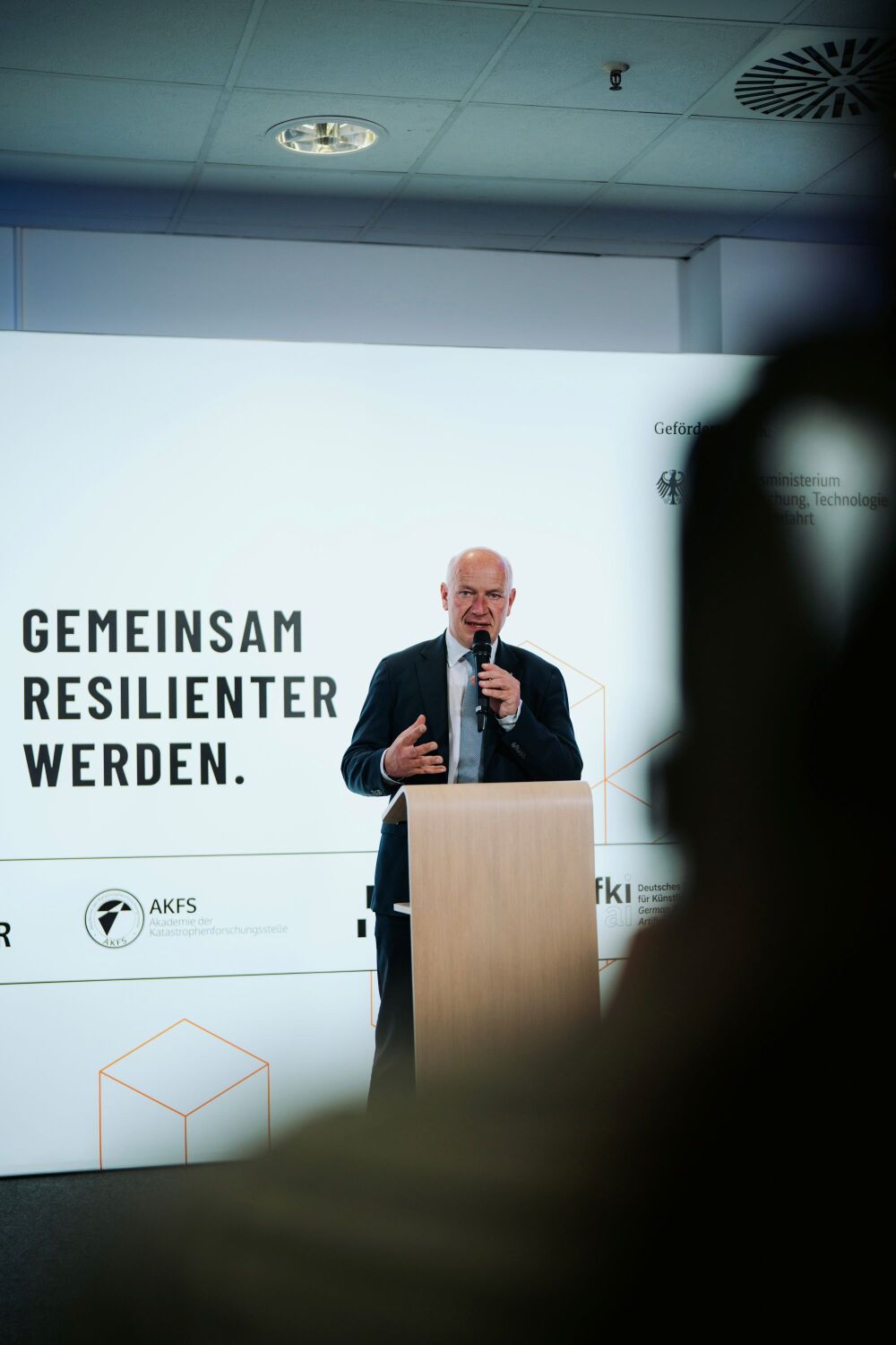 Kai Wegner spricht vor einem weißen Banner mit der Aufschrift "Gemeinsam resilienter werden"