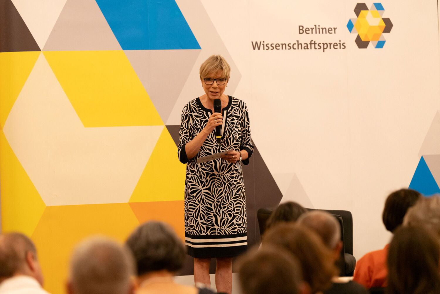 Christine Richter hält ein Mikrofon in der Hand und spricht auf der Bühne des Berliner Wissenschaftspreises