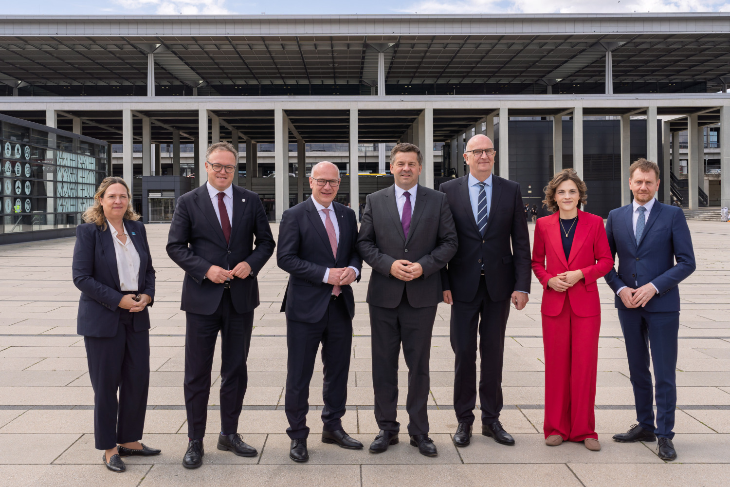 Die Regierungschefin und Regierungschefs der ostdeutschen Länder sowie die Ostbeauftragte posieren vor dem Flughafen BER in Schönefeld