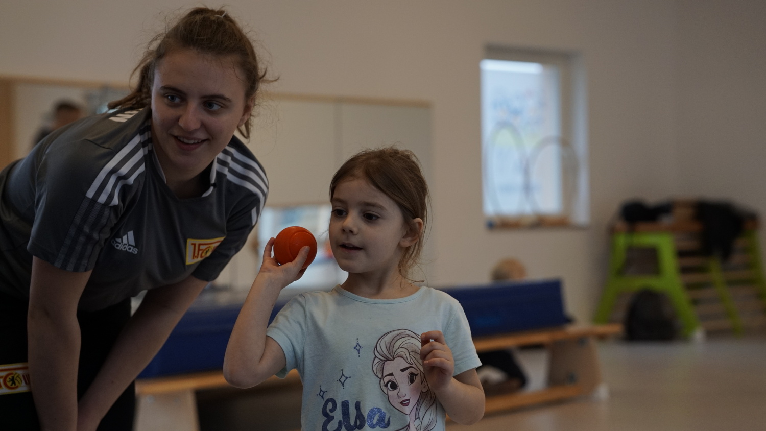Sportlerin mit einem Kind in einer Turnhalle