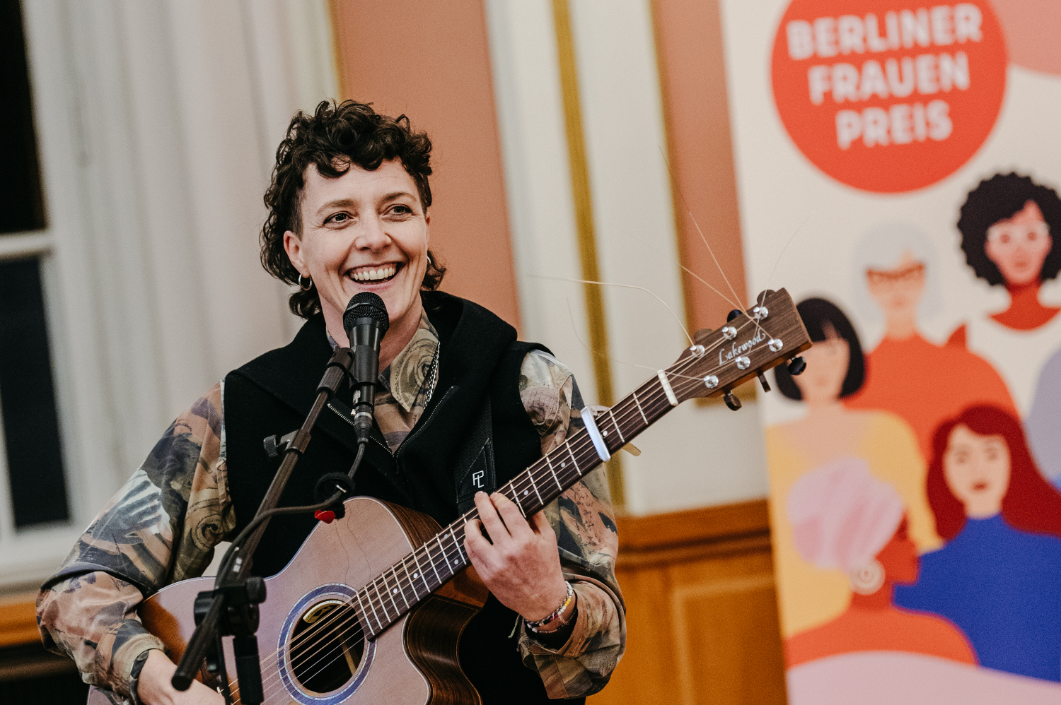 Solokünstler*in LIN sorgt mit Gitarre für Stimmung im Roten Rathaus.