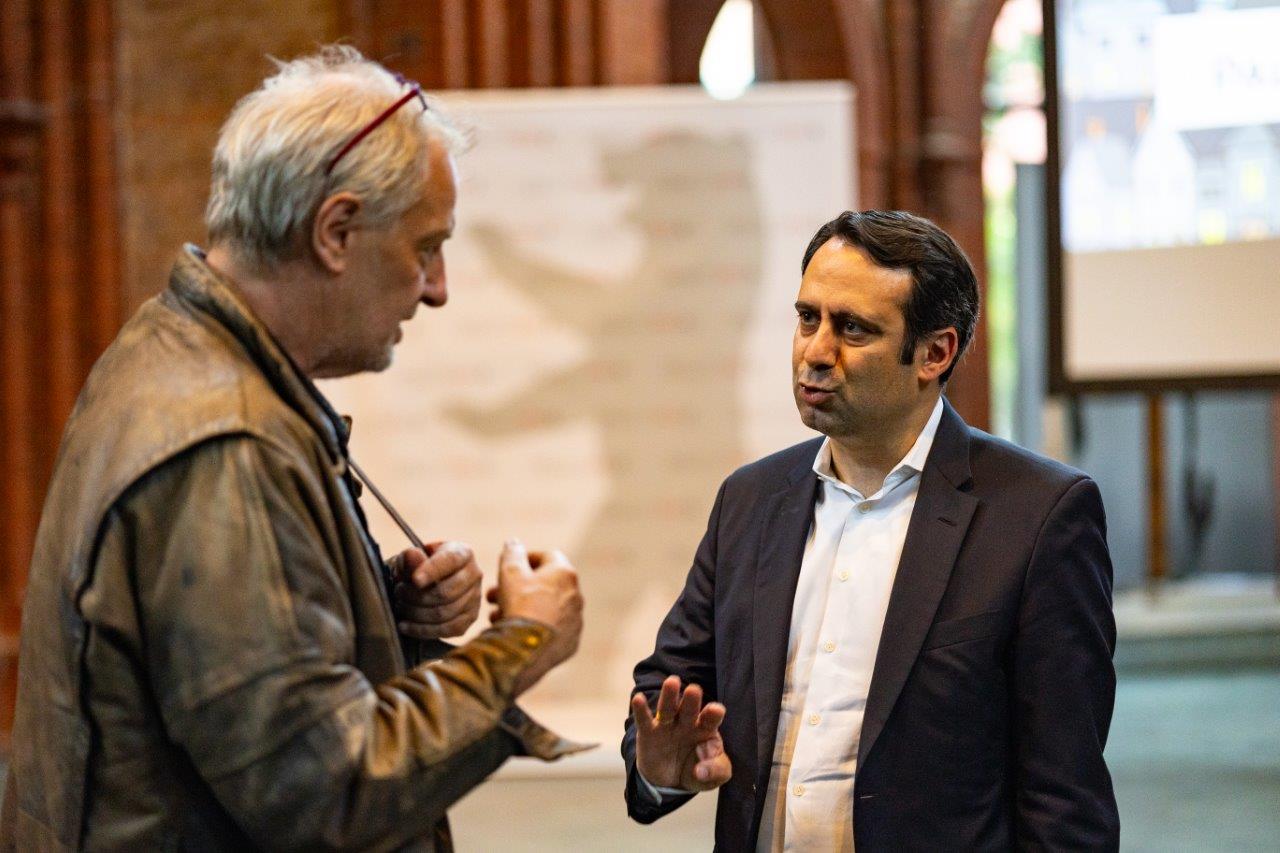 Sozialstaatssekretär Aziz Bozkurt im Gespräch mit einem Konferenz-Teilnehmer.