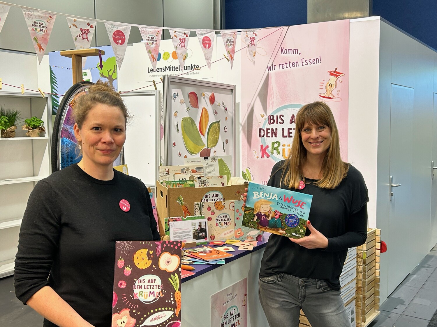 Zwei Mitarbeiterinnen präsentieren den Stand von Restlos Glücklich in der Berlin-Halle