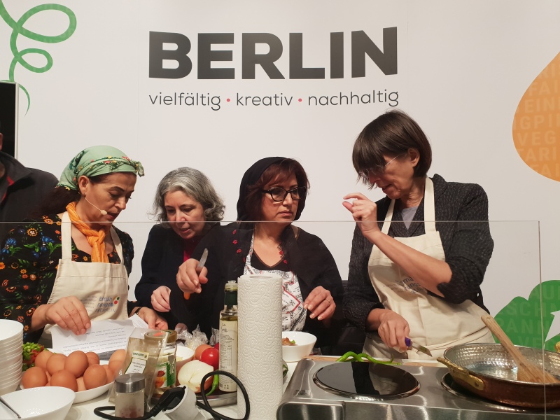 Kochaktion mit der Staatssekretärin Gottstein und türkischen Frauen auf der Bühne der Berlin-Halle