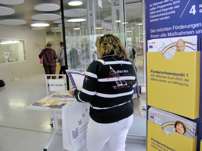 Gäste vor der EFRE-Infosaule und den Give-Aways