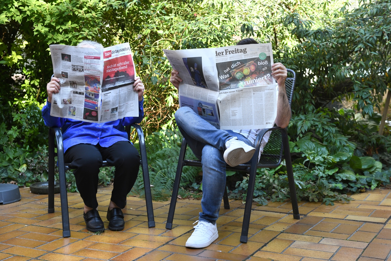 Zwei Menschen lesen Zeitungen im Lesegarten der Bruno-Lösche-Bibliothek