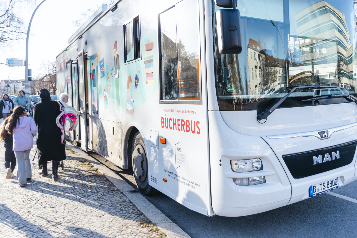 Bücherbus quer von vorn mit Menschen am Eingang