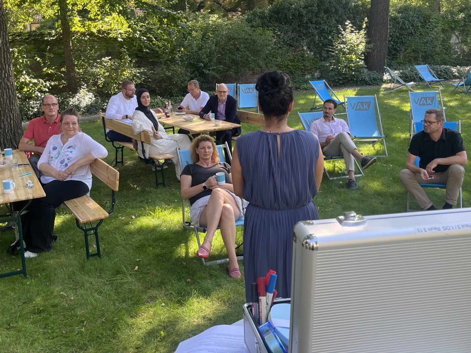 Teilnehmende auf Liegestühlen hören einer sprechenden Person zu