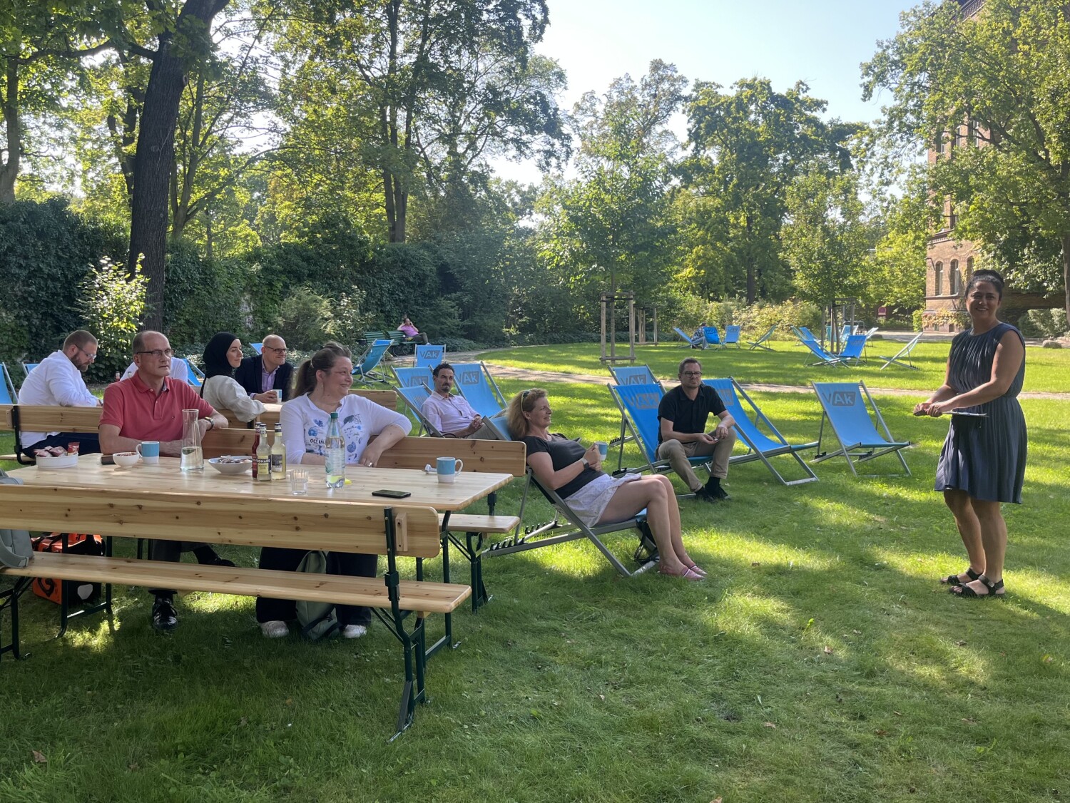 Teilnehmende auf Liegestühlen hören einer sprechenden Person zu