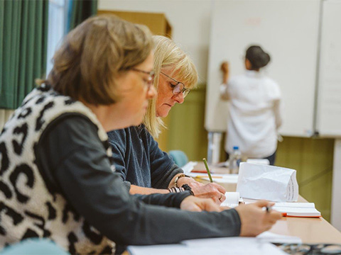 Kursszene im Spanischunterricht - zwei Frauen konzentrieren sich auf Schreibarbeit