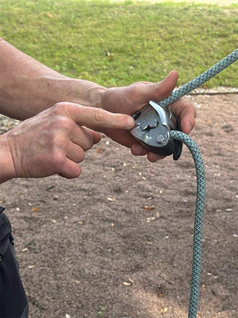 Hände halten eine Kletter-Rolle. Ein Finger deutet auf ein Detail.