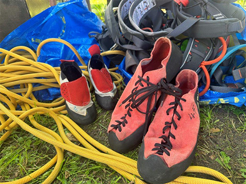 Kletterseil, Kletterschuhe, Klettergurte liegen zusammen im Gras