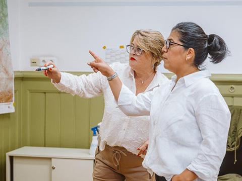 Yetlaneci Alcaraz mit Kursteilnehmerin. Beide zeigen auf das Whitebord (Schreibtafel)