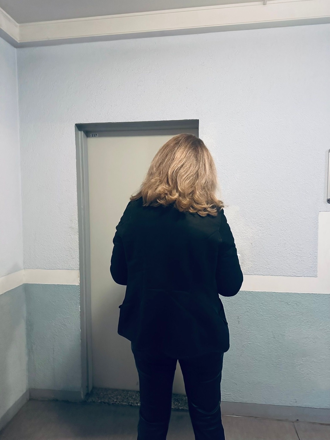 Eine Gerichtsvollzieherin steht vor der Wohnungstür